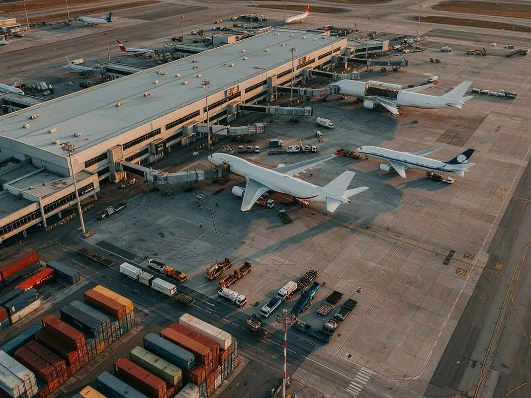 Vista aérea ilustrativa de un aeropuerto con aviones de carga y contenedores.